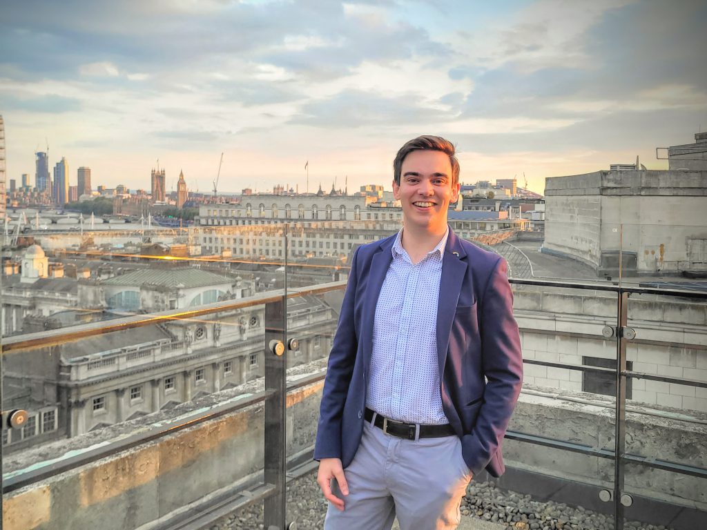 Jake Orros standing on the 8th floor balcony of Bush House with Views of Westminster in the background as the sunsets. 