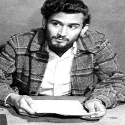 Sam Selvon sat at a desk holding papers.