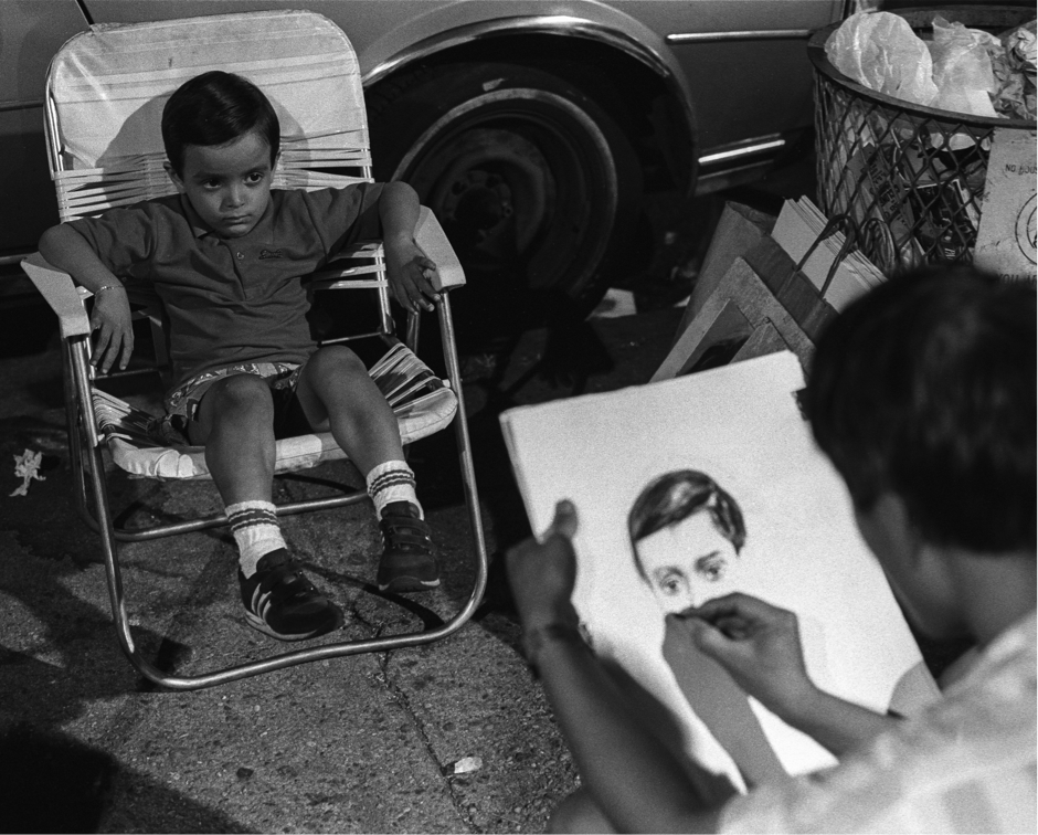 A photograph of a young boy swamped in an fold up chair getting his portrait done 