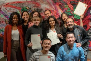 Ten people holding certificates and smiling at the camera