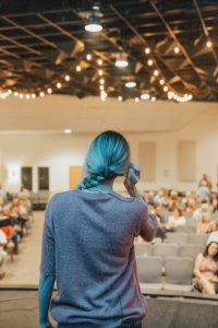 Image of woman standing in front of a lecture hall full of students