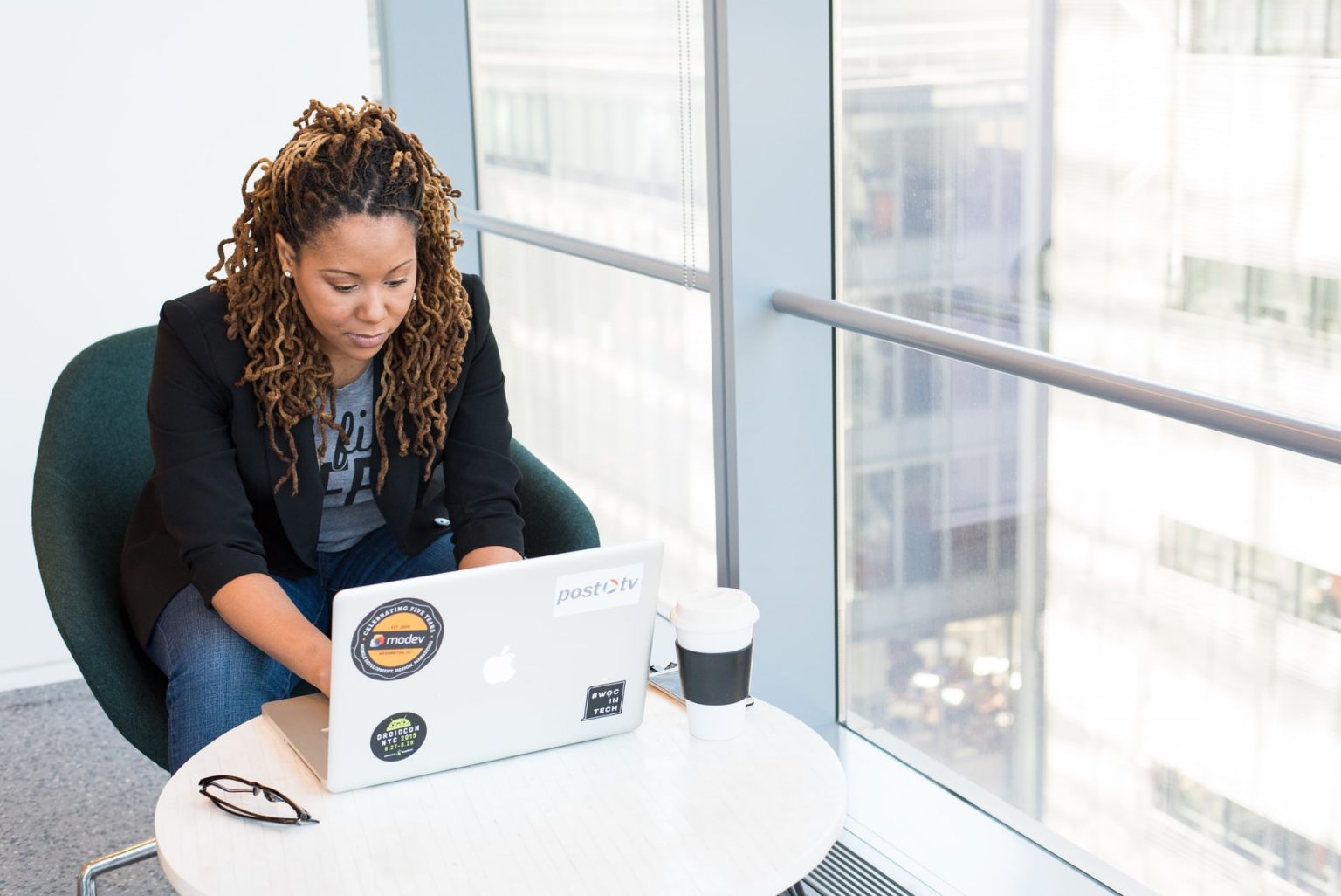 Image of black female employer using computer by a large window
