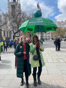Two people standing below a green umbrella