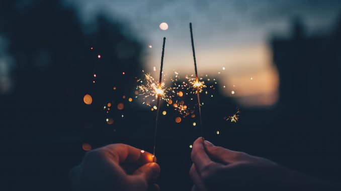 Two hands, sparklers at dusk