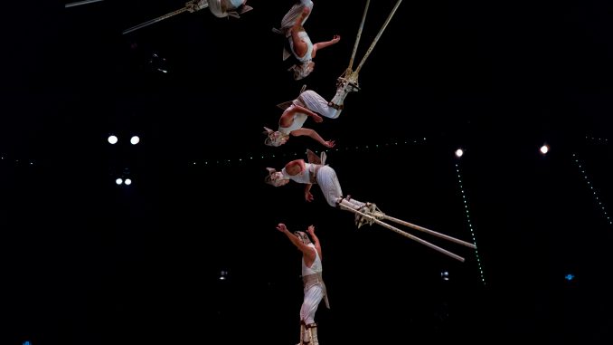 Circus acrobats balance on each other while juggling