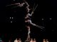 Circus acrobats balance on each other while juggling