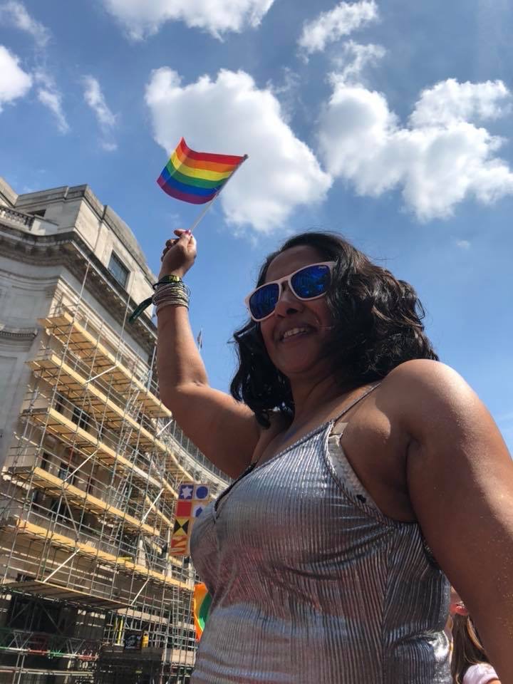Sarah Guerra at Pride parade waving a pride flag.