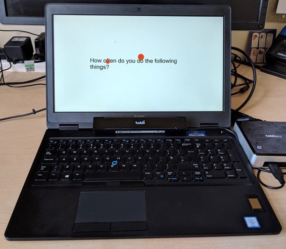Laptop with black text and red dots on white background, displaying eye-tracker unit setup