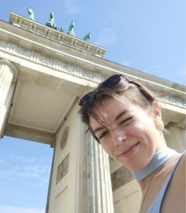 Photo of Emilie in Berlin, in front of the Brandenburg Gate, blue skies above
