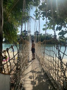 Photo of Raza on a rope bridge on a tropical beach, while on exchange in Singapore.