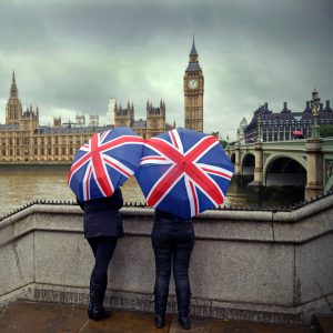 Two people holding umbrellas overlooking the Houses of Parliament